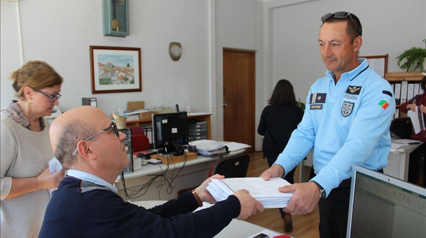 Diretor do agrupamento de escola de Gouveia entrega ao chefe Pires, da PSP, os trabalhos para serem deixados na casa de cada aluno. Foto: Liliana Carona