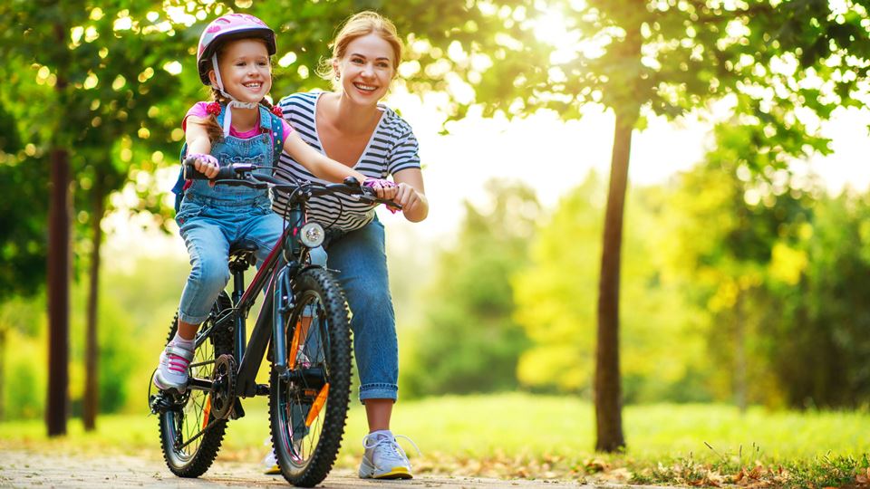 Mãe ensina filha a andar de bicicleta